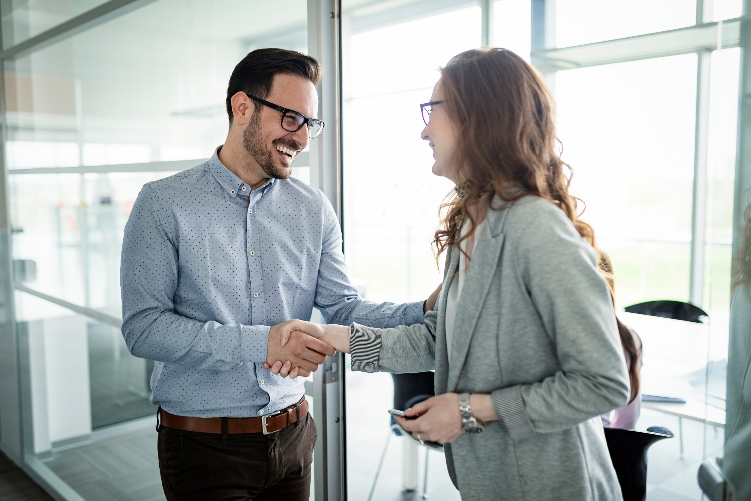 A sales professional shaking hands with a customer, showing a buying signal