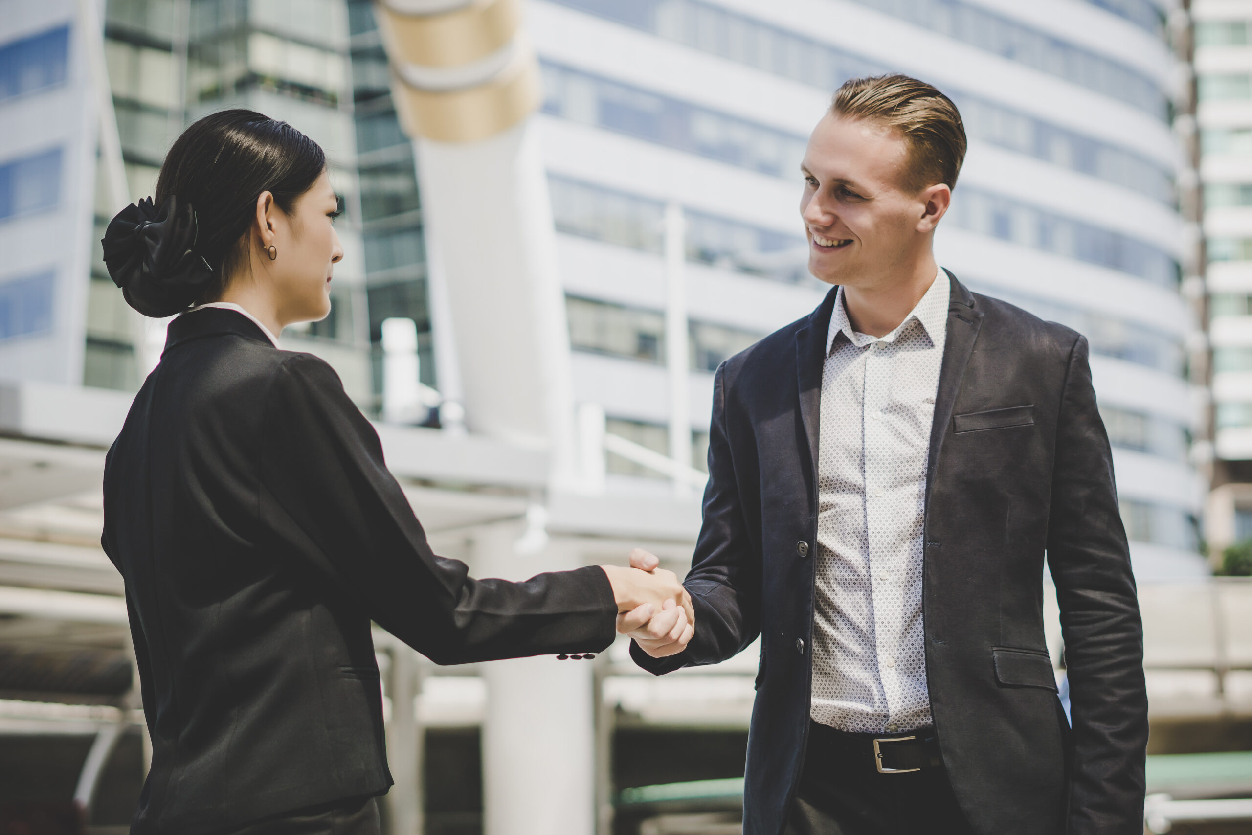 A sales professional with a client shaking hands symbolizing customer engagement.